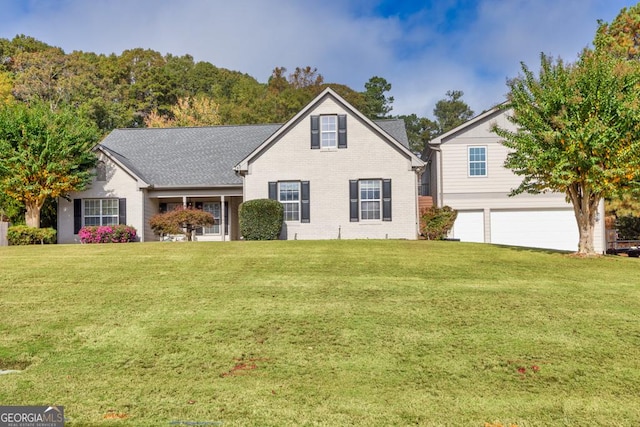 traditional-style home with an attached garage, brick siding, a front yard, and a shingled roof