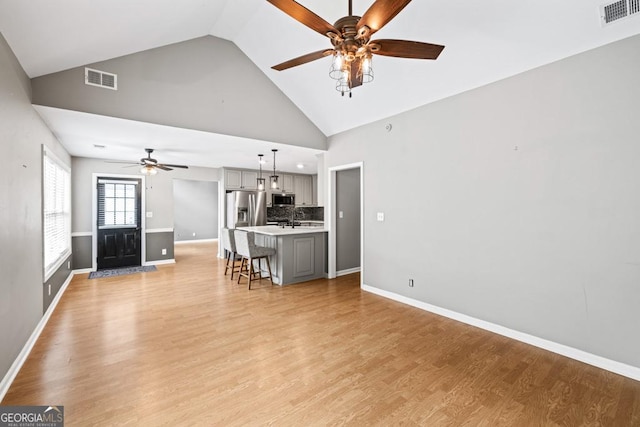 unfurnished living room featuring visible vents, baseboards, light wood-style flooring, ceiling fan, and a sink