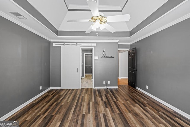 unfurnished bedroom featuring a tray ceiling, wood finished floors, visible vents, and crown molding