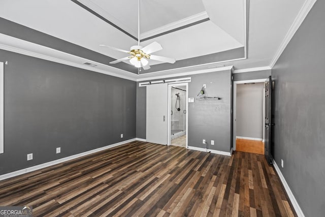 unfurnished bedroom featuring a barn door, visible vents, a raised ceiling, and wood finished floors