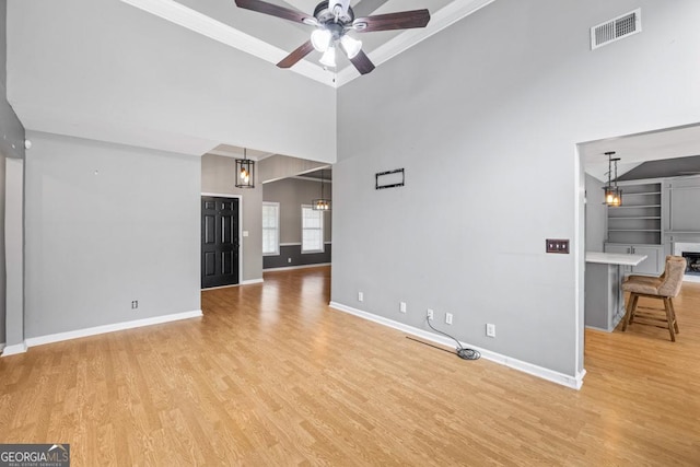 unfurnished living room with light wood finished floors, baseboards, visible vents, a towering ceiling, and ceiling fan with notable chandelier