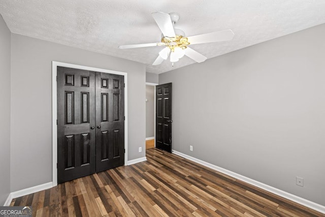 unfurnished bedroom featuring baseboards, a ceiling fan, wood finished floors, a textured ceiling, and a closet