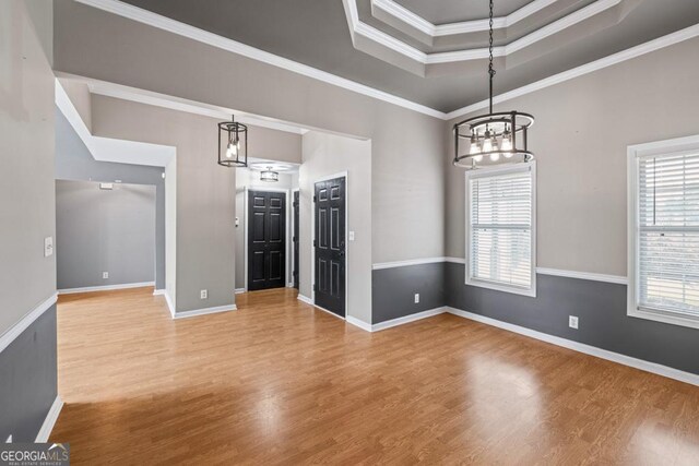 interior space with hardwood / wood-style flooring, a notable chandelier, a raised ceiling, and crown molding