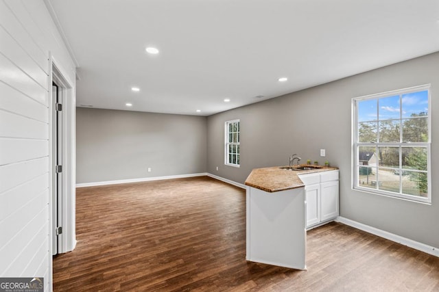 kitchen with a peninsula, dark wood finished floors, white cabinetry, and recessed lighting