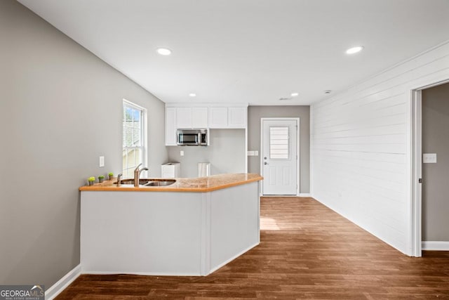 kitchen with recessed lighting, dark wood-type flooring, a sink, white cabinetry, and stainless steel microwave