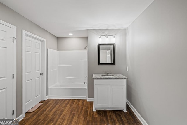 bathroom with wood finished floors, bathtub / shower combination, vanity, and baseboards