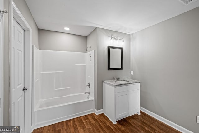 bathroom featuring tub / shower combination, vanity, baseboards, and wood finished floors