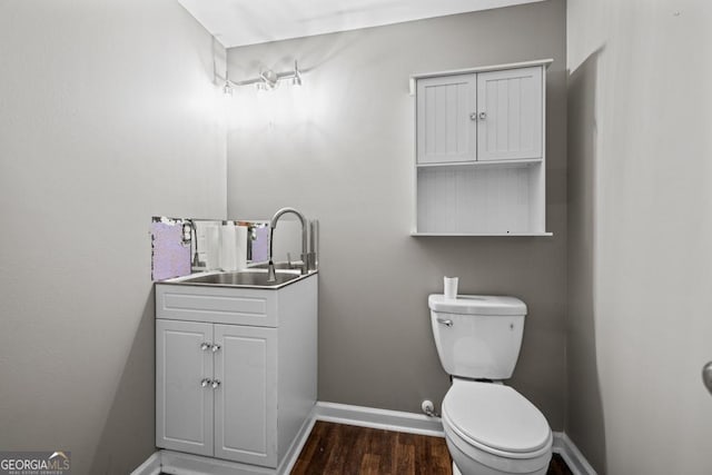 bathroom featuring toilet, vanity, baseboards, and wood finished floors