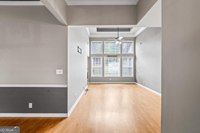 empty room featuring a ceiling fan, crown molding, baseboards, and wood finished floors