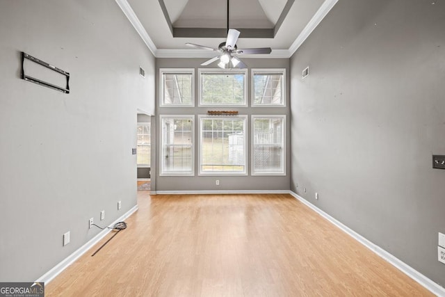 unfurnished room featuring crown molding, baseboards, a raised ceiling, and wood finished floors