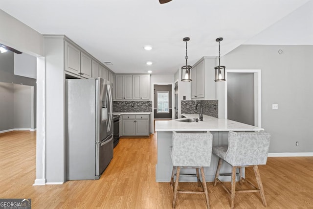 kitchen with stainless steel fridge with ice dispenser, a peninsula, gray cabinets, black range, and a sink