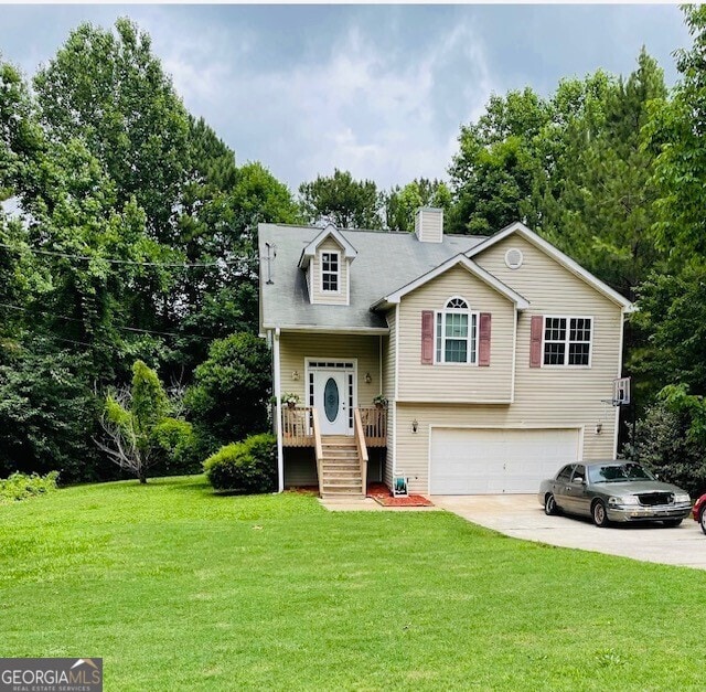 raised ranch featuring a garage and a front lawn