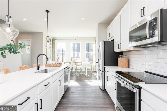 kitchen featuring appliances with stainless steel finishes, dark hardwood / wood-style flooring, hanging light fixtures, and sink