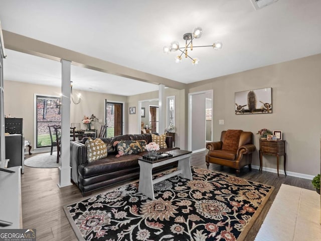 living room featuring a chandelier, dark wood-type flooring, and decorative columns