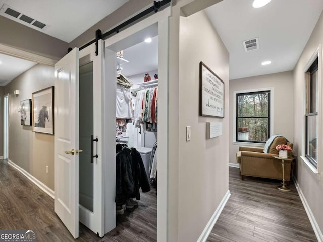 corridor featuring a barn door and dark wood-type flooring