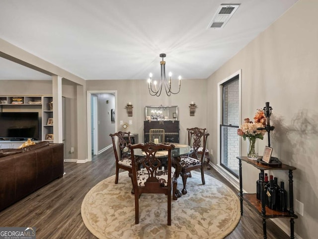 dining space with dark hardwood / wood-style floors and an inviting chandelier