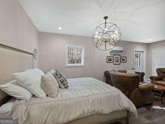 bedroom with a wall mounted air conditioner, hardwood / wood-style flooring, and a notable chandelier