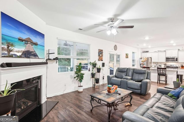 living room with ceiling fan and dark wood-type flooring