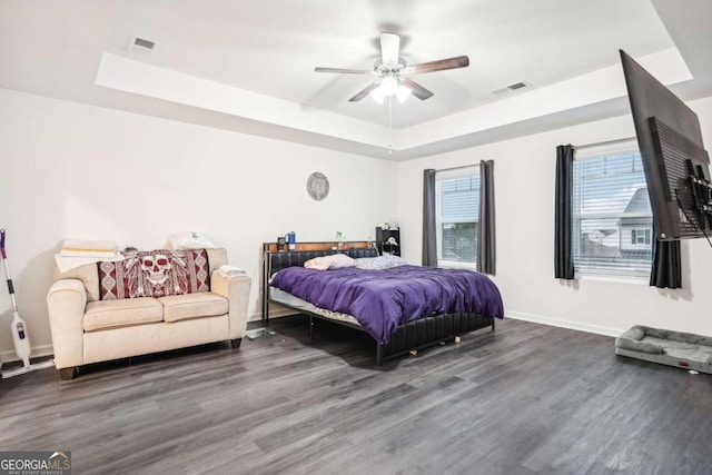 bedroom with ceiling fan, a raised ceiling, and dark wood-type flooring