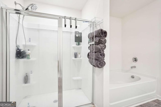 bathroom with wood-type flooring and shower with separate bathtub