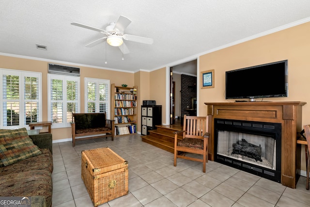 tiled living room with ceiling fan, a textured ceiling, and ornamental molding