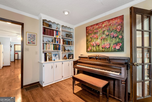 misc room featuring a textured ceiling, light hardwood / wood-style flooring, and ornamental molding