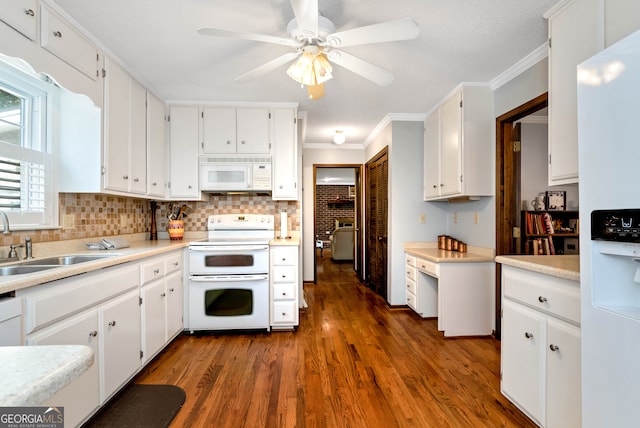 kitchen featuring ornamental molding, white appliances, sink, white cabinets, and dark hardwood / wood-style floors