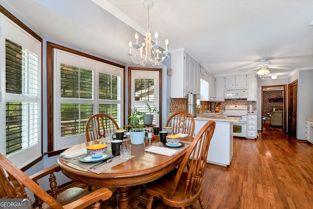 dining room featuring ceiling fan with notable chandelier, hardwood / wood-style flooring, a wealth of natural light, and crown molding