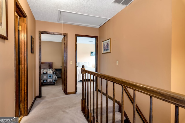 corridor with light carpet and a textured ceiling