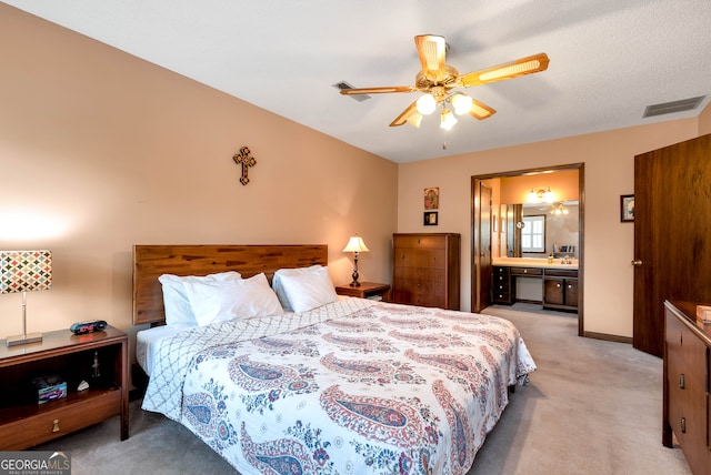 bedroom featuring a textured ceiling, ceiling fan, light carpet, and connected bathroom