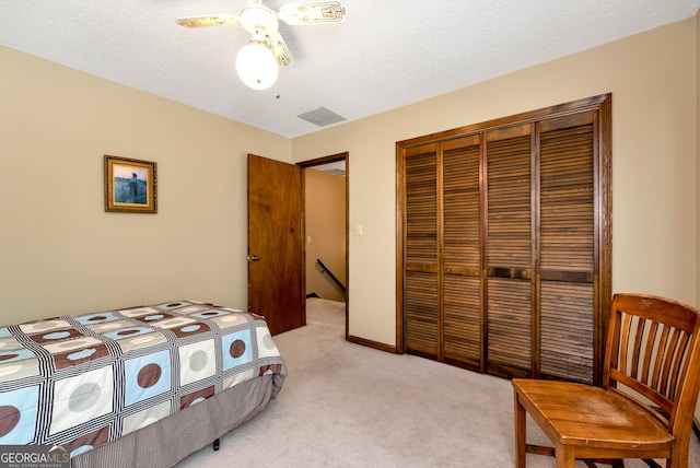 carpeted bedroom featuring ceiling fan, a closet, and a textured ceiling