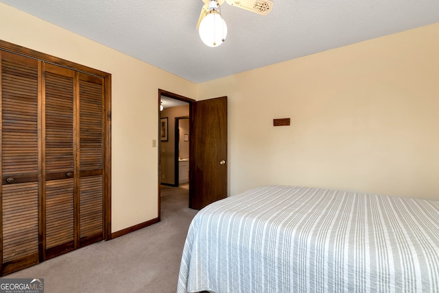 carpeted bedroom with a textured ceiling, a closet, and ceiling fan