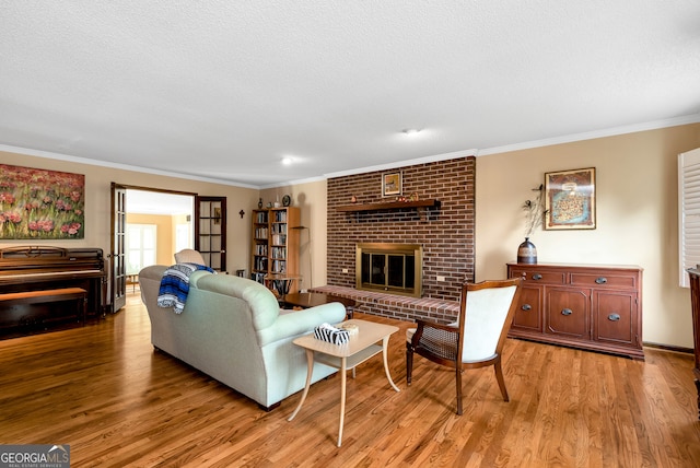 living room with a fireplace, a textured ceiling, light hardwood / wood-style flooring, and crown molding