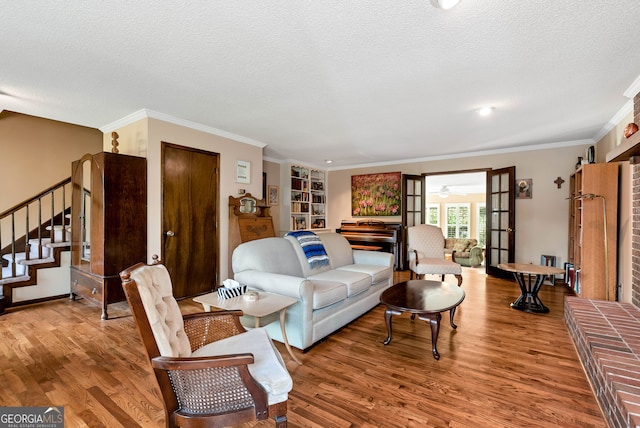 living room featuring crown molding, french doors, wood-type flooring, and a textured ceiling