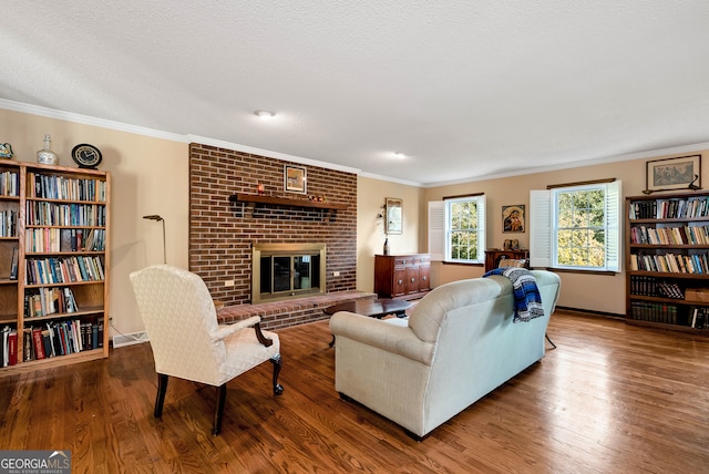 living room with hardwood / wood-style floors, ornamental molding, a fireplace, and a textured ceiling