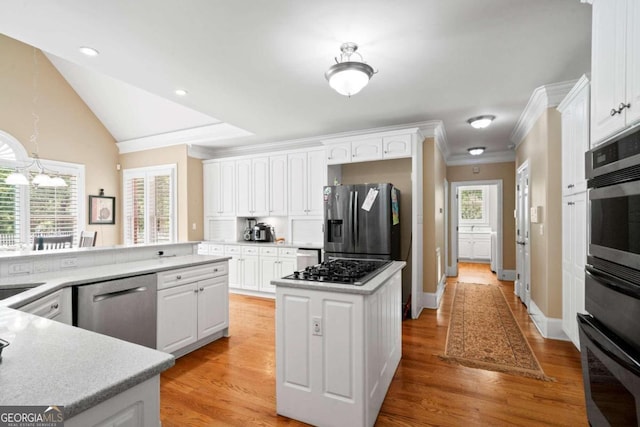 kitchen featuring a wealth of natural light, hanging light fixtures, stainless steel appliances, light hardwood / wood-style floors, and white cabinets