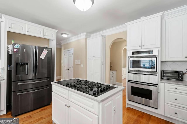 kitchen featuring appliances with stainless steel finishes, white cabinetry, light wood-type flooring, and tasteful backsplash