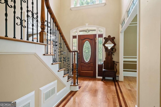 entryway with a towering ceiling and wood-type flooring