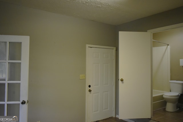 bathroom with tile patterned flooring, a textured ceiling, and toilet