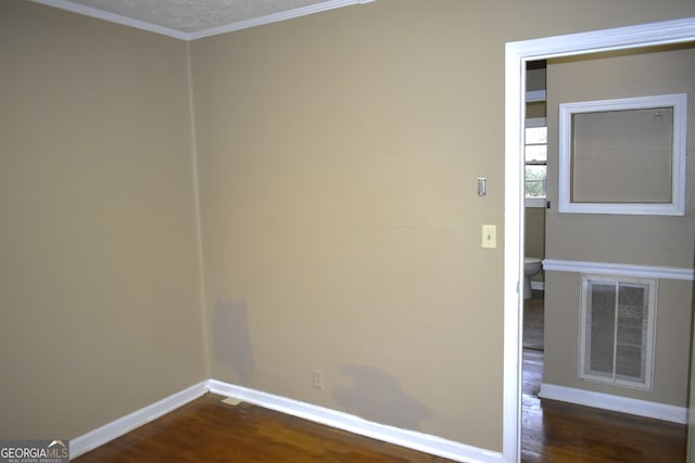 empty room featuring a textured ceiling, dark hardwood / wood-style flooring, and crown molding