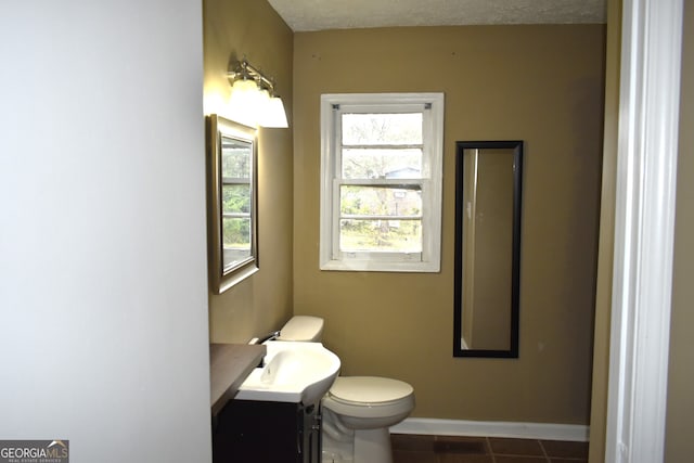 bathroom with tile patterned flooring, vanity, toilet, and a textured ceiling