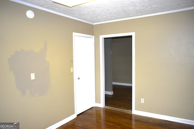 spare room with a textured ceiling, dark hardwood / wood-style floors, and ornamental molding