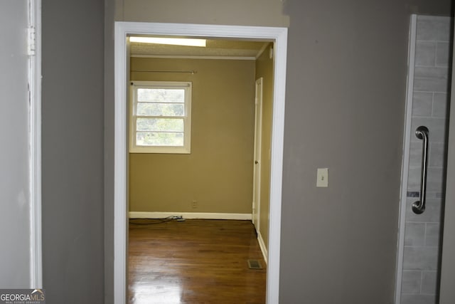 hallway with wood-type flooring and crown molding