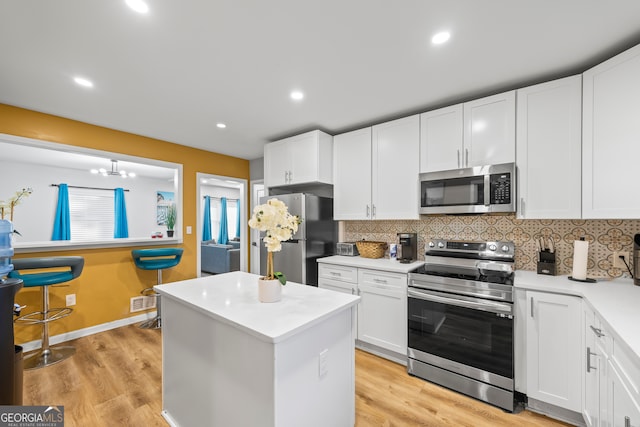 kitchen with decorative backsplash, stainless steel appliances, an inviting chandelier, light hardwood / wood-style floors, and white cabinetry