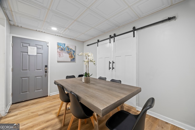 dining area featuring a barn door and light hardwood / wood-style flooring