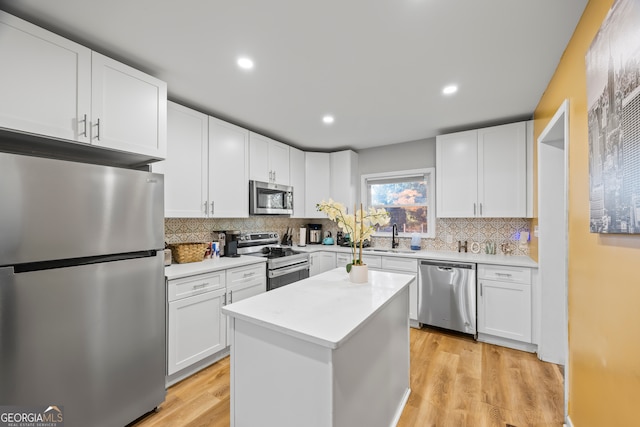 kitchen with white cabinetry, light hardwood / wood-style flooring, a kitchen island, and stainless steel appliances