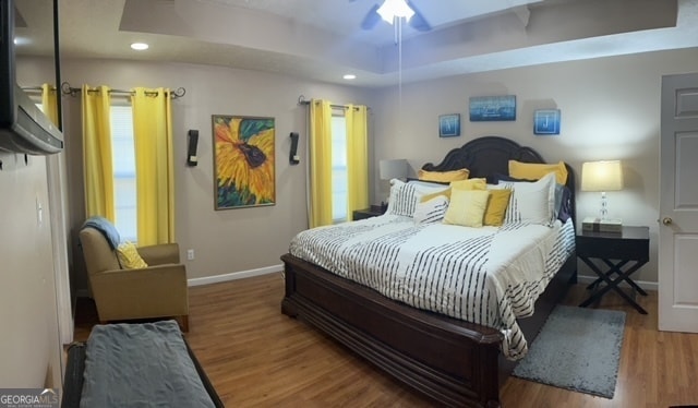 bedroom featuring hardwood / wood-style floors, ceiling fan, and a raised ceiling