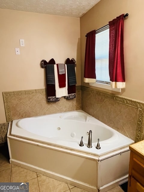 bathroom with tile patterned floors, a bathtub, vanity, and a textured ceiling