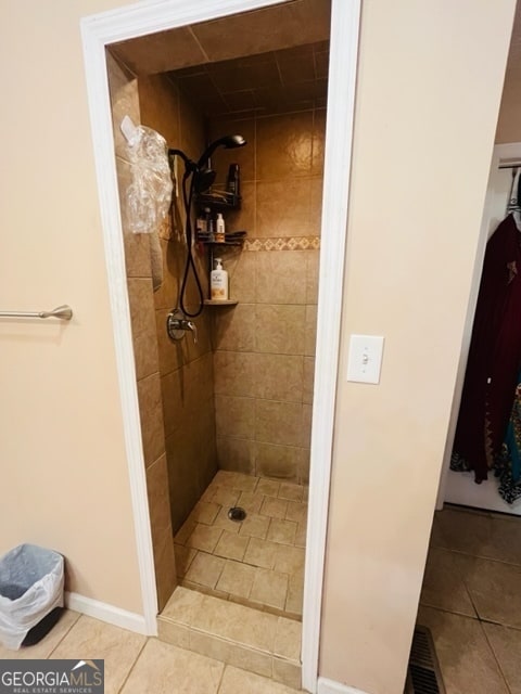 bathroom with tiled shower and tile patterned floors