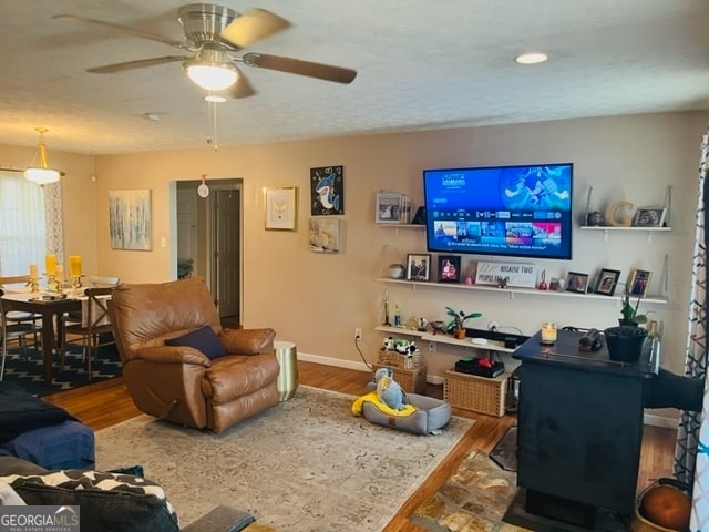 living room featuring ceiling fan, wood-type flooring, and a textured ceiling